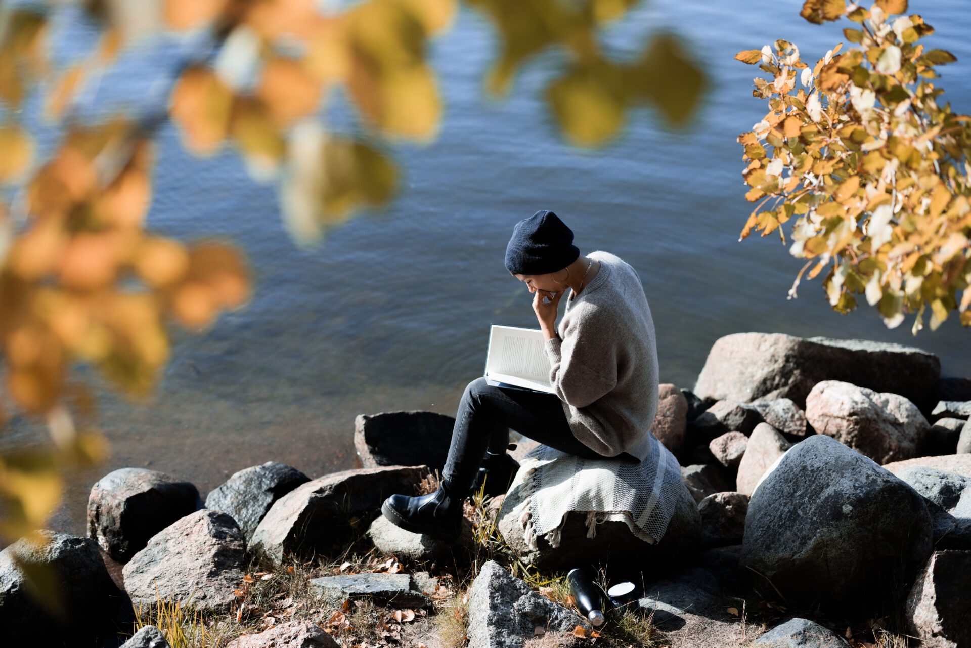 Henkilö lukee meren äärellä.